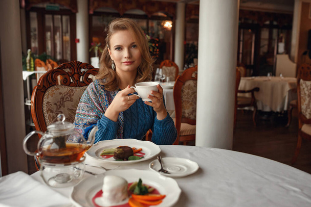 Beautiful smiling women drinking tea at cozy cafe. Businesswomen take a break with teacup. lifestyle photo in a stylish cafe. concept of a pleasant time, rest and relaxation. delicious tea and cake - Photo, Image