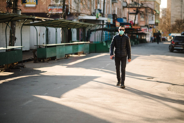 Coronavirus. Man wearing medical protective mask walking on street.  Corona virus COVID-19. Air pollution, virus, Chinese pandemic concept. Virus, pandemic, panic concept. - Foto, afbeelding
