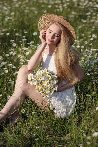 beautiful young woman in a camomile field in a picturesque valley. happy young lady and spring green nature, harmony concept. the idea of self-care, a healthy lifestyle and a positive attitude - Fotografie, Obrázek