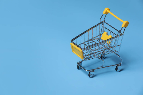 close-up of shopping trolley on blue background with some copy space. empty shopping cart on blue background. - Valokuva, kuva
