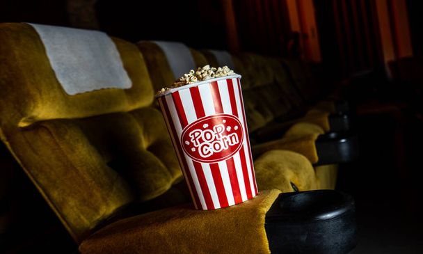 Gelbe Sitzreihe mit Popcorn auf Stuhl im Kinosaal - Foto, Bild