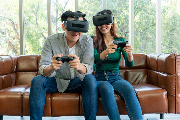 Jovem casal asiático feliz jogando videogames na sala de estar. Pessoas alegres se divertindo com o conceito de jogos de computador
. - Foto, Imagem