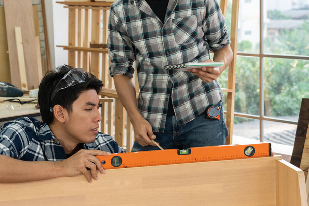 Asztalos dolgozik fa kézműves műhelyben, hogy készítsen építőanyagot vagy fabútorokat. A fiatal ázsiai ácsok professzionális eszközöket használnak a kézművességhez. DIY asztalos és asztalos munka koncepciója. - Fotó, kép