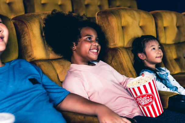 Üç çocuk eğleniyor ve sinemada film izlemekten zevk alıyor. - Fotoğraf, Görsel