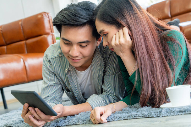 Boldog ázsiai pár használja tabletta, miközben feküdt szőnyegen a nappaliban padlón. Szerelem és kapcsolat fogalma. - Fotó, kép