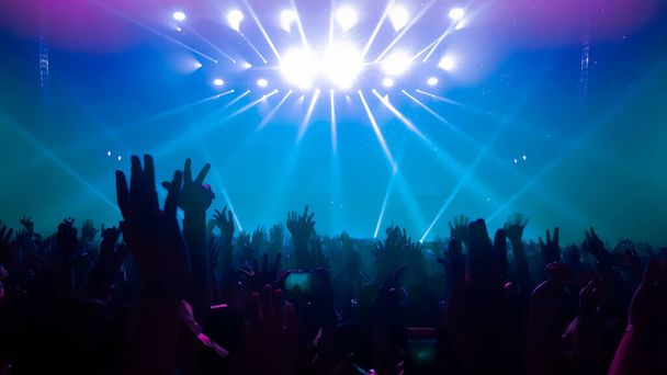 La gente felice balla nel concerto di festa del DJ del nightclub e ascolta la musica danzante elettronica dal DJ sul palco. La folla allegra di silhouette festeggia la festa di Capodanno 2020. Stile di vita delle persone DJ vita notturna. - Foto, immagini