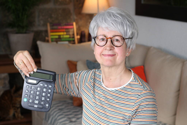 Inquiète femme âgée exploitation calculatrice
 - Photo, image