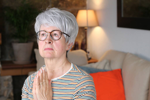Starsza kobieta modli się w domu - Zdjęcie, obraz