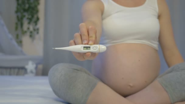 Zwangere vrouw met een thermometer in haar handen - Video