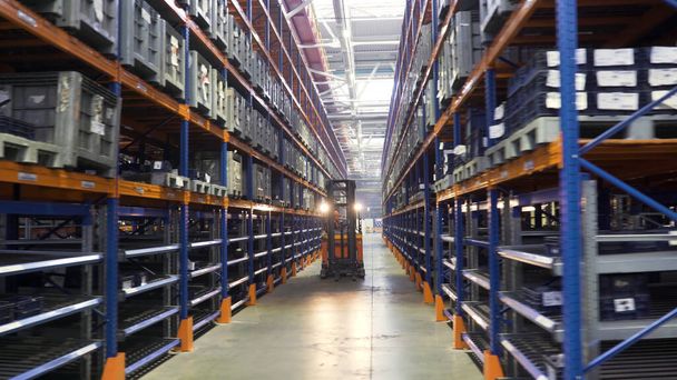 Warehouse in a factory with technical goods for mechanical engineering. Scene. Storing at warehouse shelves with workers using stacker trucks for boxes organization. - Photo, Image