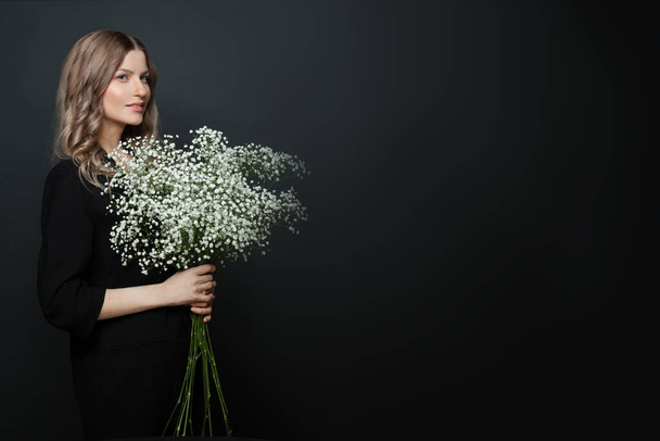 Perfect woman holding white flowers on black background - Photo, Image
