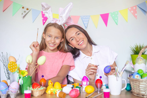 Mother and her little daughter painting eggs. Happy family preparing for Easter. - Foto, imagen