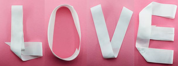 Word Love napsal bílou stuhu nebo pásku na růžové pozadí. Valentýn, Ženská, Svatba, Den matek, přání k výročí. 14. února. Horní pohled na slovo LOVE hláskováno. - Fotografie, Obrázek