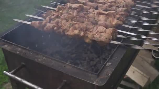 Wypoczynek, jedzenie, ludzie i koncepcja wakacji. smażyć mięso na ognisku na imprezie ulicznej. gotowanie mięsa na grillu - Materiał filmowy, wideo