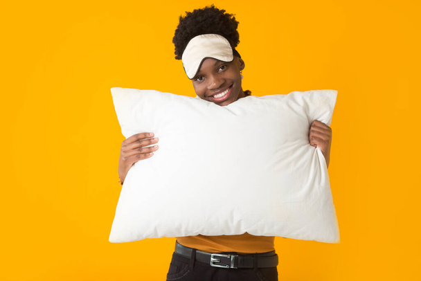 beautiful young african woman on a yellow background with a pillow - Fotografie, Obrázek