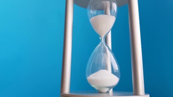 Reloj de arena elegante sobre un fondo azul. Concepto-negocio tiempo dinero, educación, tiempo se está acabando, gestión del tiempo, recurso de tiempo, tiempo completo, plazo
 - Metraje, vídeo