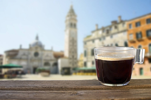タワーとカラフルな建物、イタリアとヴェネツィアのテーブルとイタリア広場に黒いコーヒーのガラスカップで表示されます - 写真・画像