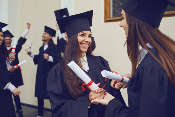 Female graduates with diplomas in their hands hugging - Foto, imagen