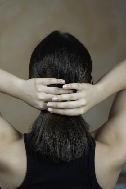 Rear view of a woman arranging her hair - Zdjęcie, obraz
