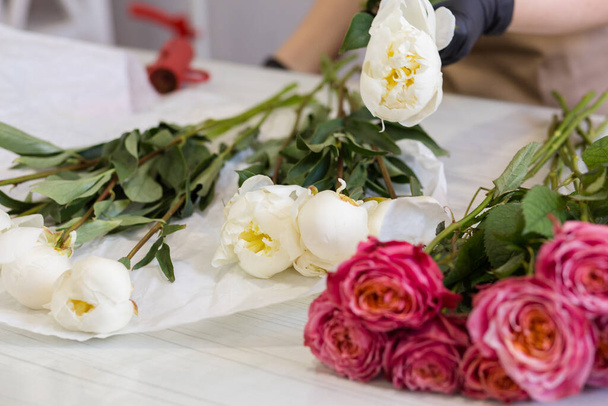fehér bazsarózsa és vörös rózsa egy virágüzletben - Fotó, kép