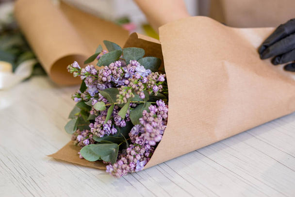 Lilás nas mãos de uma florista que cria um buquê em uma loja de flores
 - Foto, Imagem