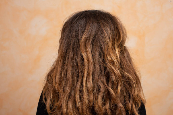 brown-blond girl with long and brittle hair seen from the shoulders - Foto, imagen