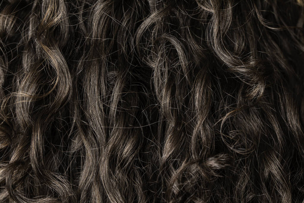 A közeli és makró nézet a sötét barna haj egy lány göndör zárak, töltse ki a keretet részletesen létre hullámos mintázatú. - Fotó, kép
