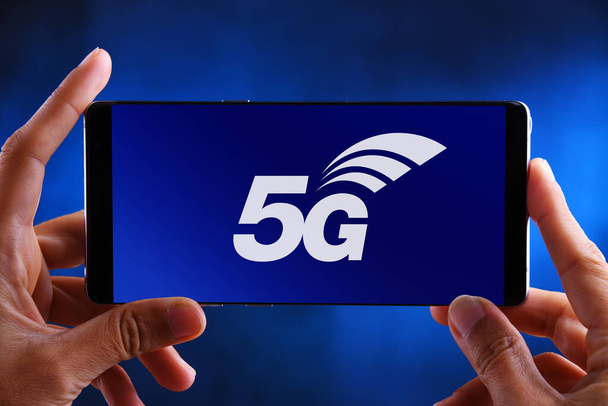 POZNAN, POL - 2020年3月26日:携帯電話データネットワークを支える第5世代無線通信技術「 5G 」のロゴを表示するスマートフォンを手に - 写真・画像