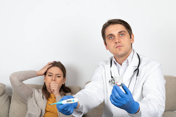 Young male doctor consulting female patient with influenza symptoms at home - Photo, image