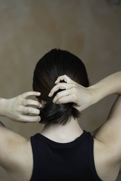Rear view of a lady arranging her hair - Φωτογραφία, εικόνα