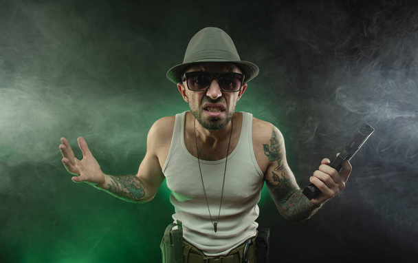 an athletic guy with a tattoo poses with a pistol - Photo, Image