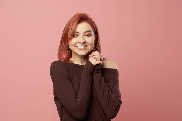 Happy woman in burgundy sweater isolated on empty pink background - Фото, изображение