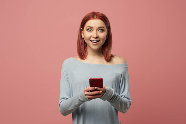 Happy girl with phone in her hands standing in studio - Foto, Imagen