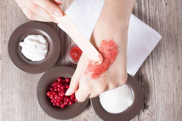 A woman applies a natural homemade scrub with a spatula. Skin care. Natural ingredients for making a scrub, sugar, cream, berry. Moisturizing, exfoliating, peeling. Home Cosmetics, Spa Treatment, Eco - Photo, Image