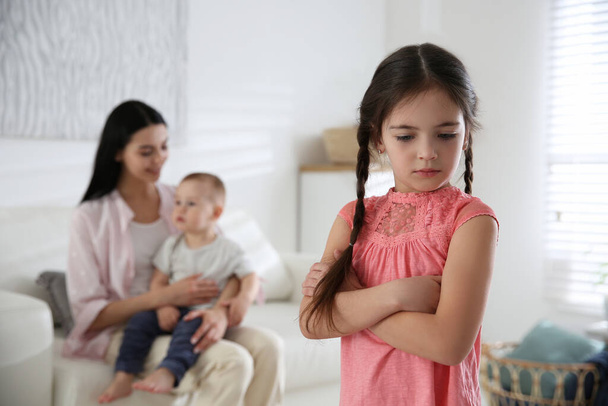 Unhappy little girl feeling jealous while mother spending time with her baby brother at home - Foto, Bild