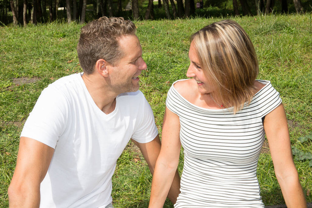 Romanttinen pari hymyilee rakastava halailu etsivät toisiaan kesäpuisto aurinkoinen päivä
 - Valokuva, kuva