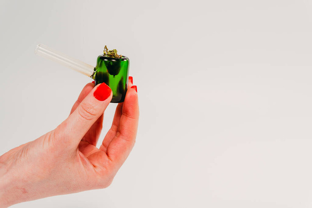 Cannabis. Female hand holds a smoking pipe with marijuana. - Fotó, kép