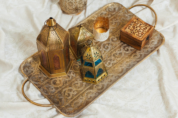 Faroles de bronce orientales en una bandeja tallada en oro detalles interiores. Faroles metálicos candelabros de estilo árabe. Decoración en diseño de estilo oriental
 - Foto, imagen