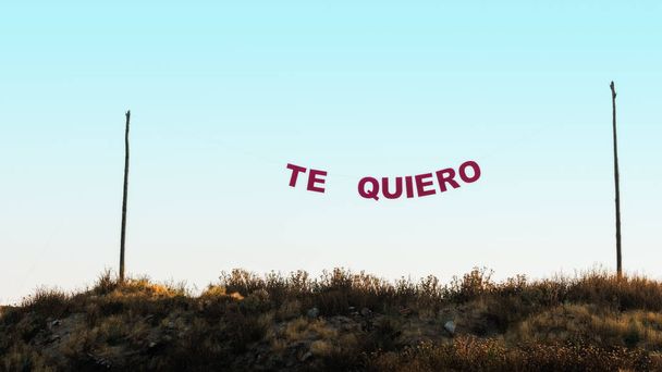 Słowa "te quiero" wisiały między dwoma słupami z liną, na niebieskim niebie. Pojęcie miłości. - Zdjęcie, obraz