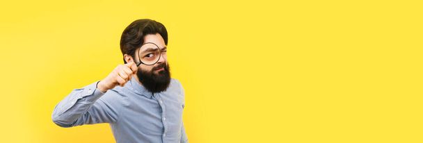 bearded man with magnifier over yellow  background, search concept, panoramic mock-up with space for text - Photo, Image
