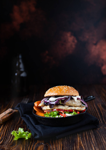 Здоровий дієтичний гамбургер із смаженою курячою ниткою, паприкою, солодкою картоплею, салатом, цибулею та грецьким йогуртом подається на сковороді на дерев'яному столі. Збільшення, копіювання простору - Фото, зображення