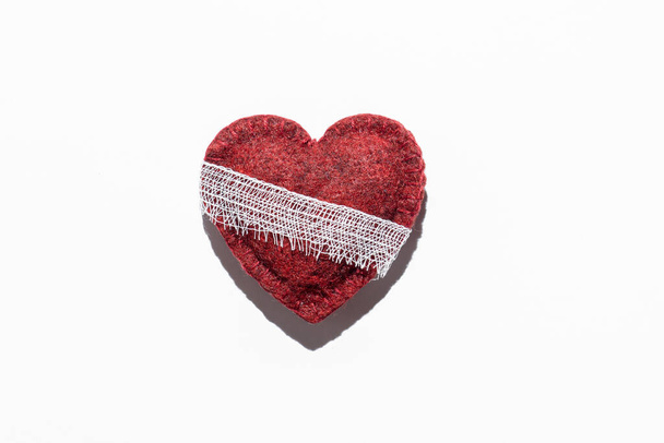red textured heart on a white background bandaged, the concept of recovery, after illness - Photo, image