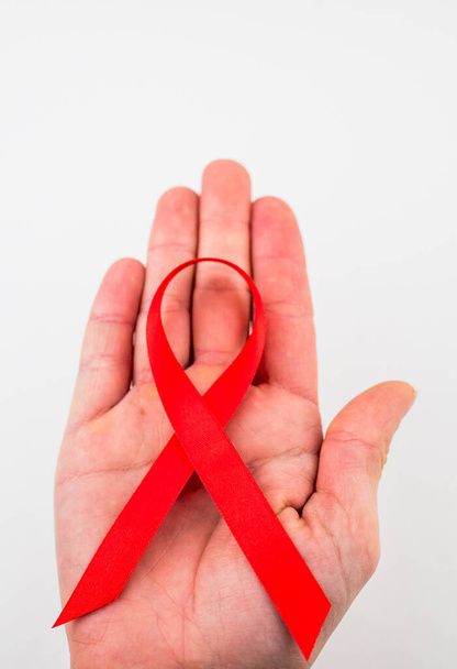 healthcare and medicine concept - female hands holding red AIDS awareness ribbon. - Zdjęcie, obraz