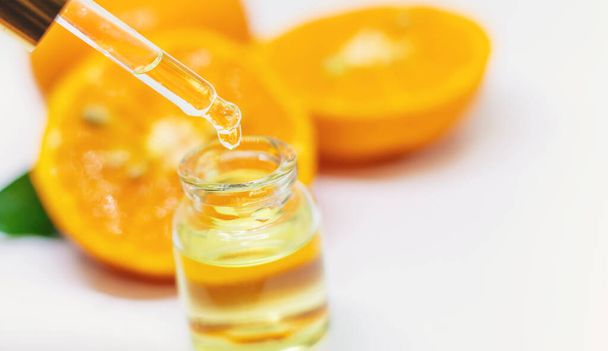 Ätherisches Orangenöl auf weißem Hintergrund. Selektiver Fokus. Lebensmittel. - Foto, Bild