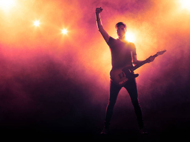 Sylwetka gitarzysty na scenie w świetle reflektorów. Koncert - Zdjęcie, obraz