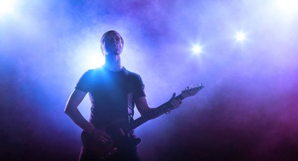 ステージ上のギター奏者のシルエット。音楽演奏。洪水灯の背景 - 写真・画像