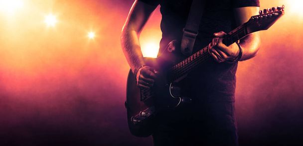 A férfi, aki reflektorfényben gitározik. Zenei előadás - Fotó, kép