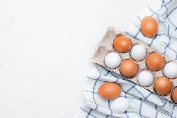 куриные яйца на проверенном кухонном полотенце на светлом столе. концепция сельскохозяйственной продукции и натуральных продуктов питания. Статья о домашних продуктах. Свежие куриные яйца. Здоровое питание - Фото, изображение