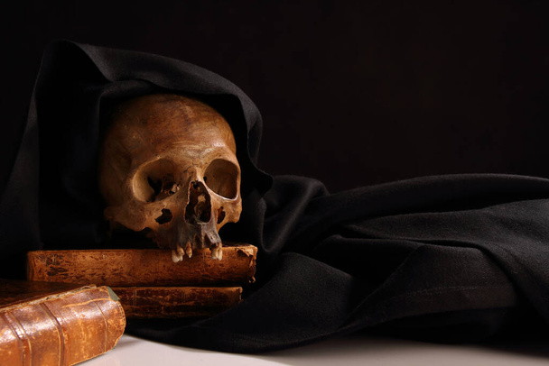 Natural human skull on the background of ancient books - 写真・画像