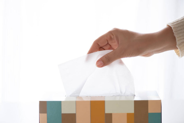 Mulher mão colhendo papel branco da caixa de tecido para prevenção da doença por Coronavírus (COVID-19). Conceito de cuidados de saúde e desinfecção
. - Foto, Imagem